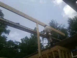 Carpenter setting a ridge beam over a new addition frame — Ice Dam Removal by Roofing Brothers in Salado