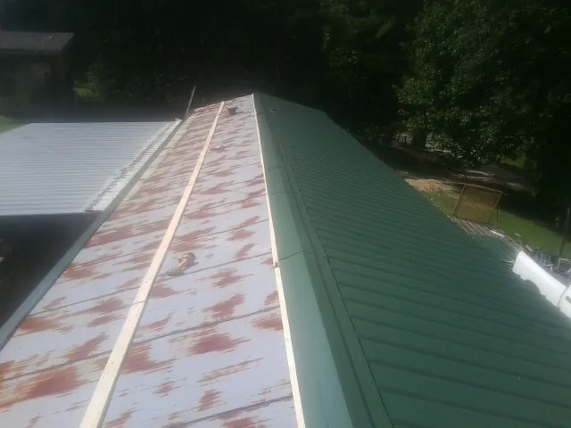 Old rusted panels beside newly installed green metal roofing — Wind Damage Roof Repair by Roofing Brothers in Salado