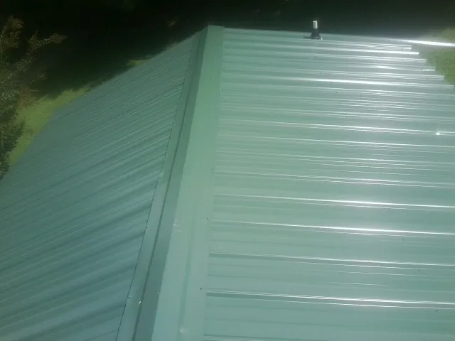 New green metal panels meeting at the ridge of a roof — Flat Roof Repair work by our crew in Salado