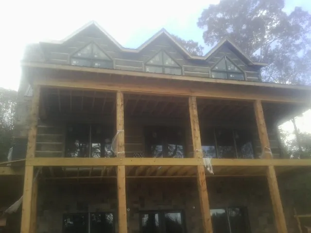 Dormers and porch framing on a large log home under construction — Roof Coating work by our crew in Salado