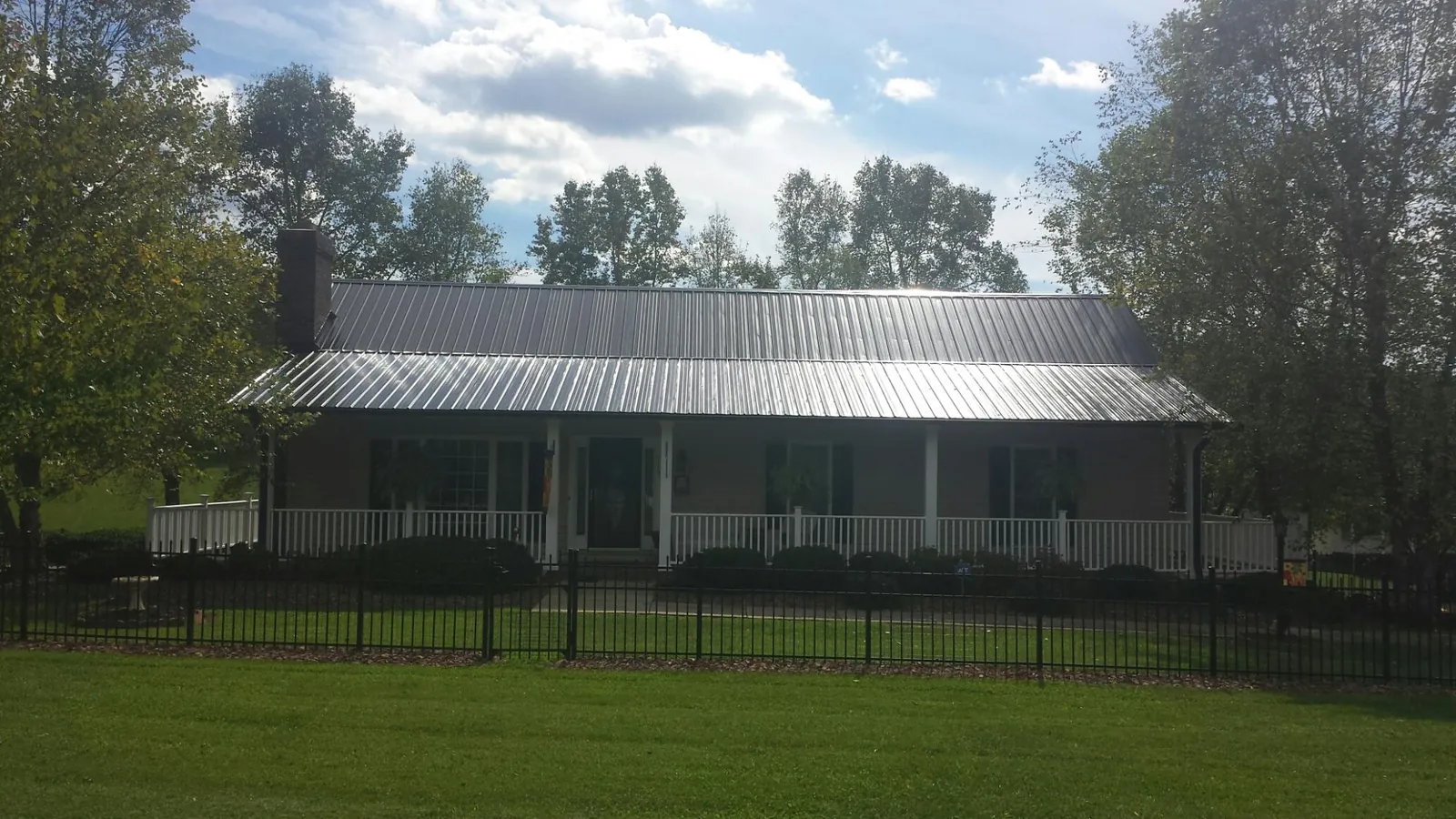 Gray metal roof on a brick ranch with a full width front porch — Gutter Guard Installation work by our crew in Salado