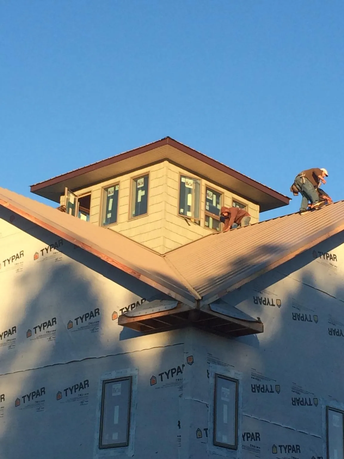Roofers working around a rooftop cupola on a new metal roof at sunset — Roof Waterproofing in Salado by Roofing Brothers